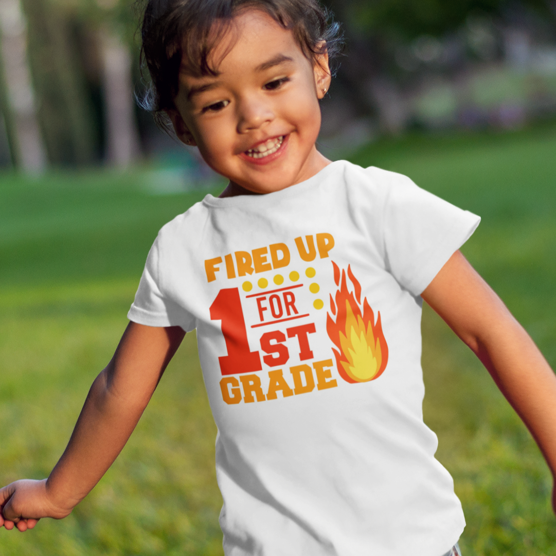 Child wearing a t-shirt with 'Fired Up for 1st Grade' text, running in a park.