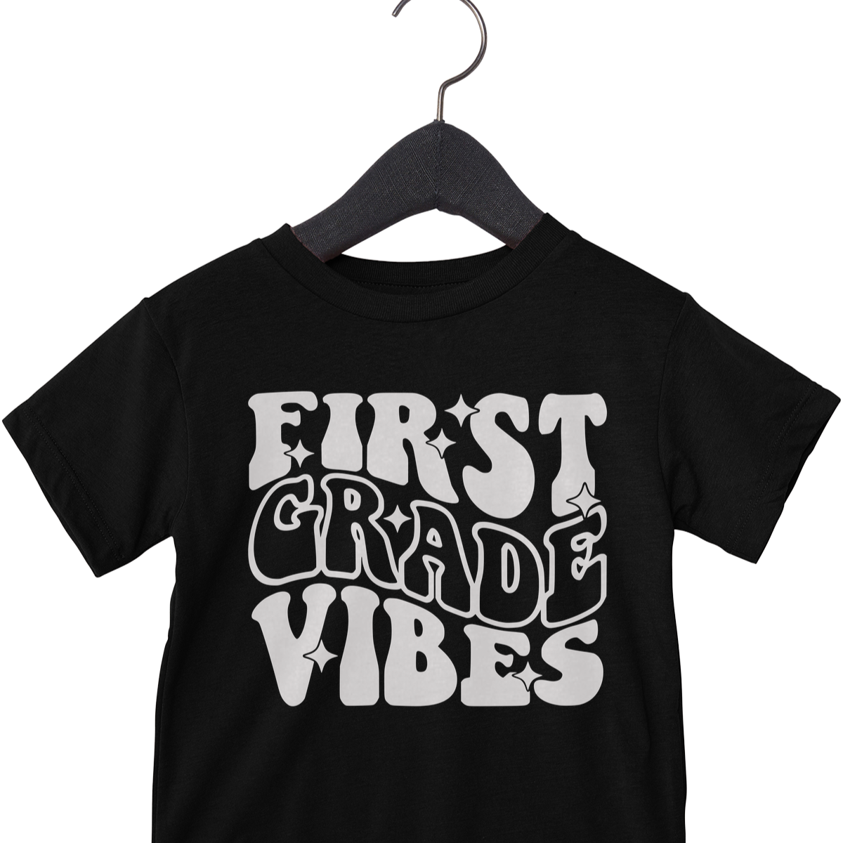 Black t-shirt with 'First Grade Vibes' text on a hanger